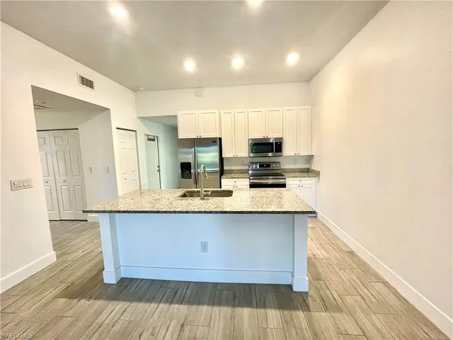 a large kitchen with stainless steel appliances granite countertop a sink and cabinets