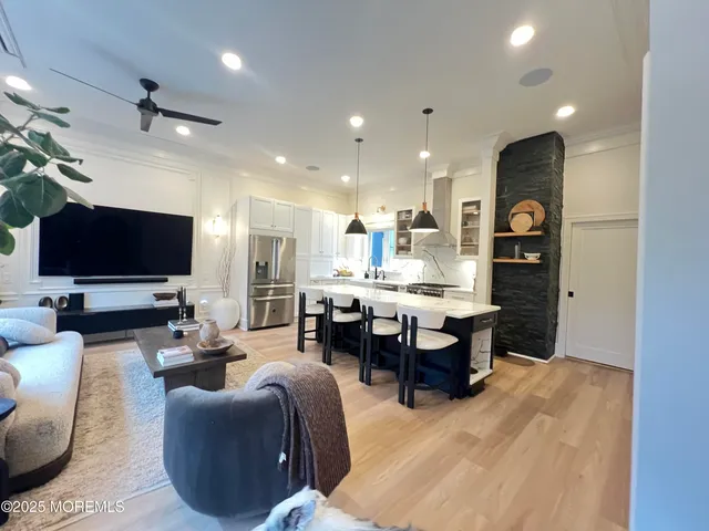 a living room with couches and kitchen view with wooden floor