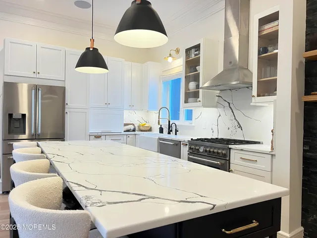 a kitchen with stainless steel appliances kitchen island granite countertop a sink a stove and white cabinets