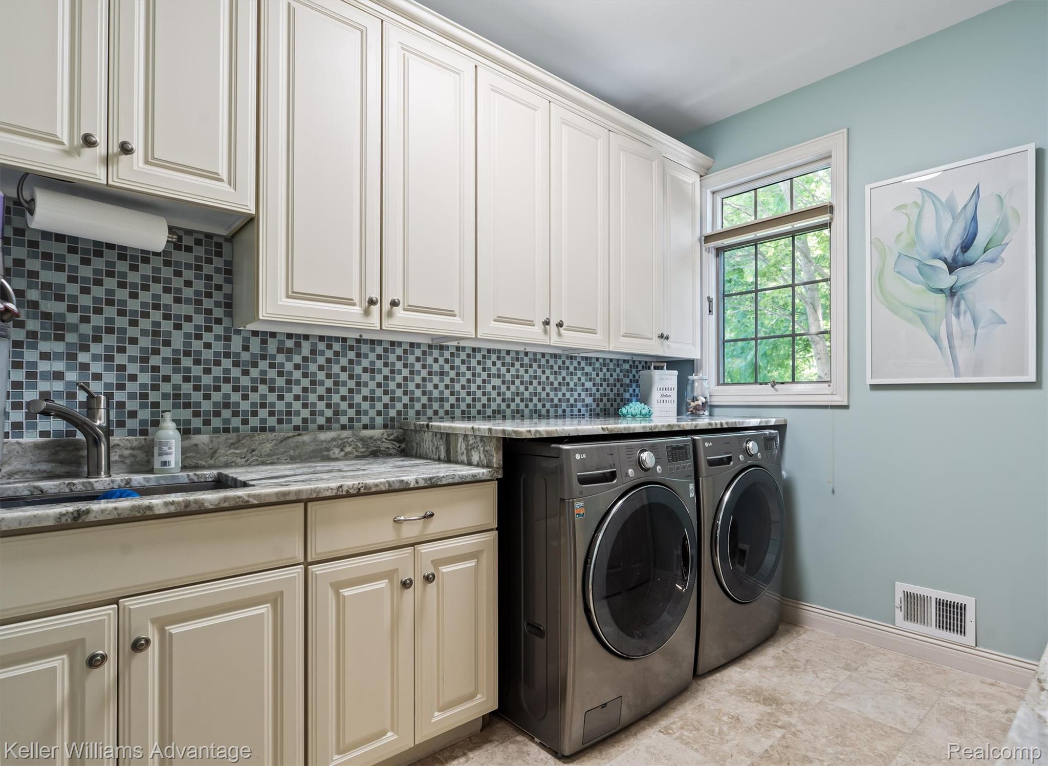 22878 Tree Top Court South Lyon, MI 48178 - Photo 14 of 75 Laundry area featuring extensive cream-colored cabinetry, a gray granite countertop, and a mosaic tile backsplash
