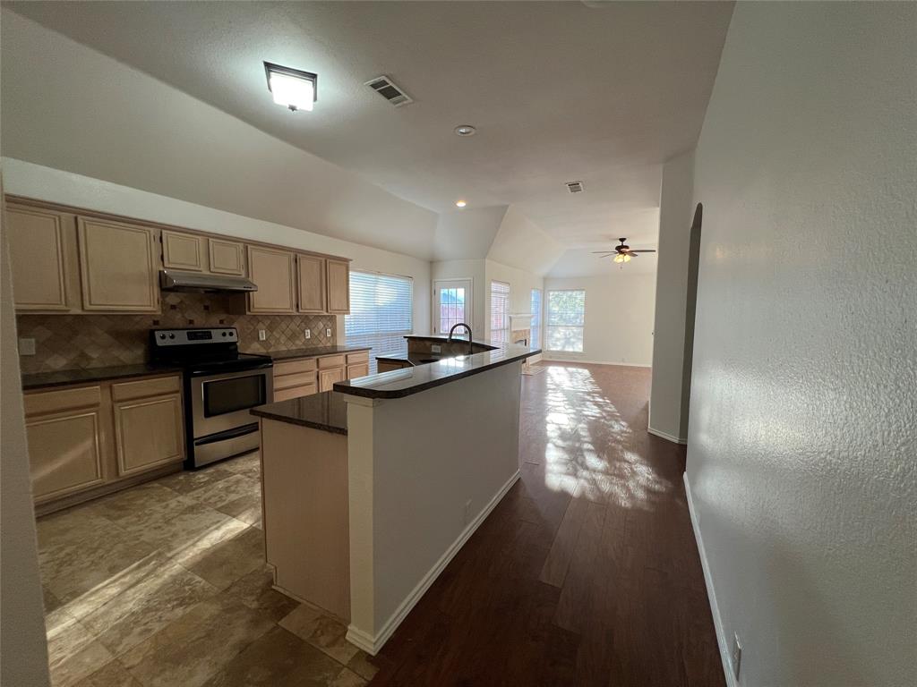 334 Touchdown Drive Irving, TX 75063 - Photo 13 of 32 Kitchen with tile flooring and wood-finish cabinetry, featuring a stainless steel range and an integrated kitchen island with a dark countertop