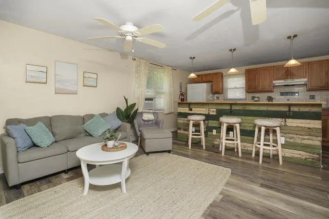 a living room with furniture a wooden floor and kitchen view