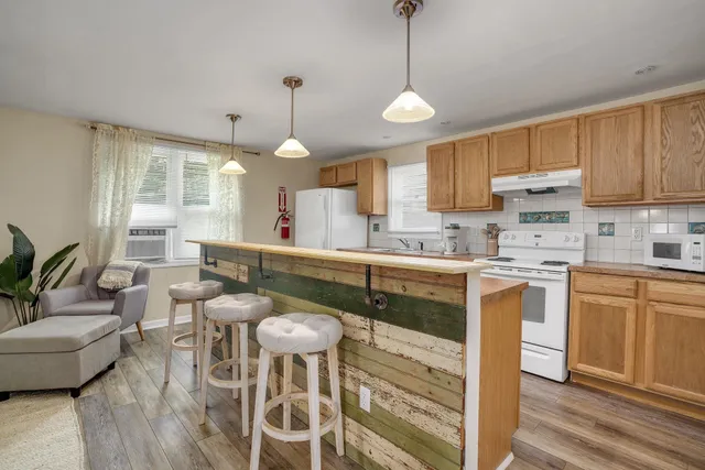 a kitchen with stainless steel appliances granite countertop a stove a sink a dining table and chairs with wooden floor