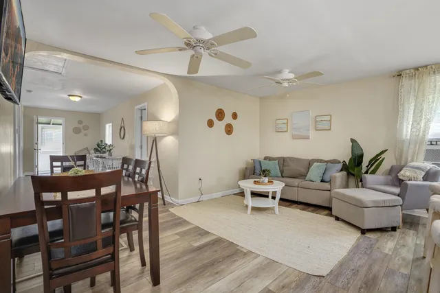 a living room with furniture kitchen view and a wooden floor