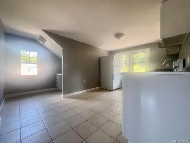 a view of an empty room with a window and a kitchen
