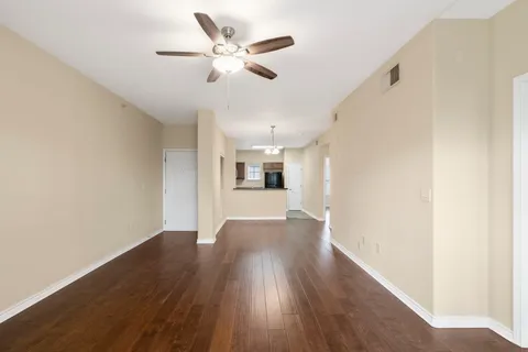 a view of a big room with wooden floor and windows