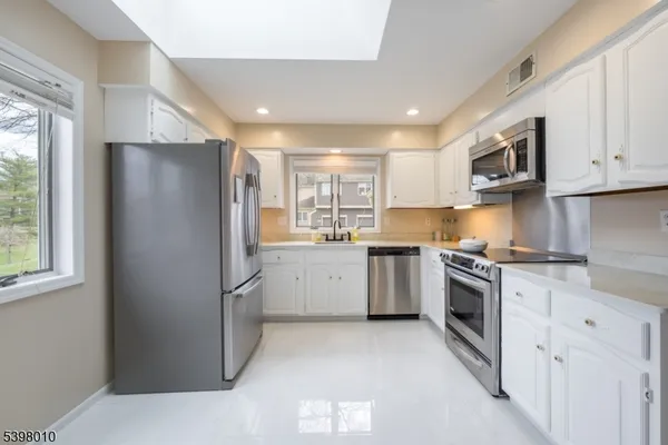 a kitchen with granite countertop white cabinets sink and stainless steel appliances