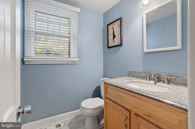 a bathroom with a granite countertop toilet sink and mirror