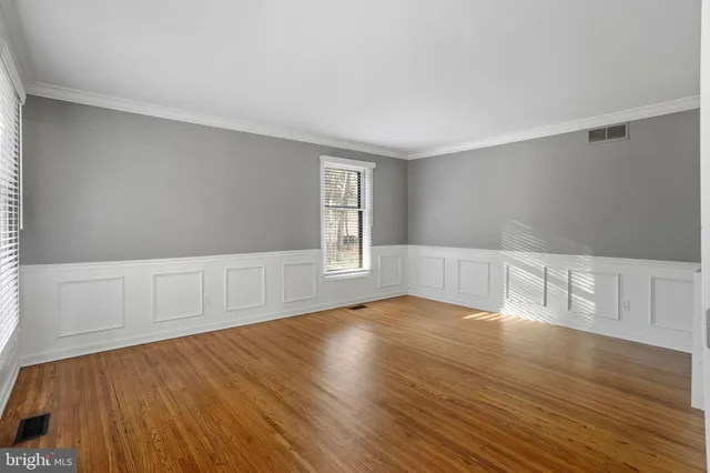a view of an empty room with window and wooden floor