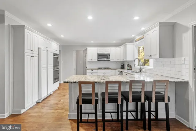 a kitchen with kitchen island a dining table chairs cabinets and stainless steel appliances