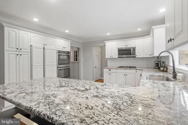 a kitchen with stainless steel appliances kitchen island granite countertop a refrigerator and a sink