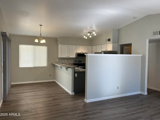 a kitchen with granite countertop a refrigerator oven a sink dishwasher and white cabinets with wooden floor