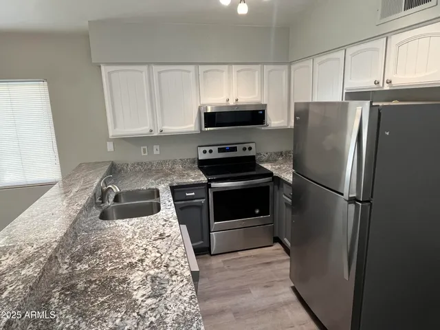 a kitchen with granite countertop a refrigerator stove and microwave