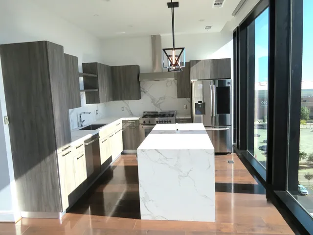 a kitchen view with stainless steel appliances kitchen island granite countertop a refrigerator a stove and a sink with wooden floor