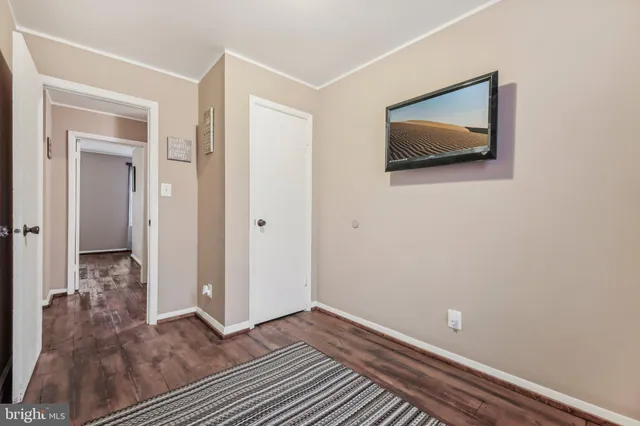 a view of a hallway with wooden floor and a bathroom