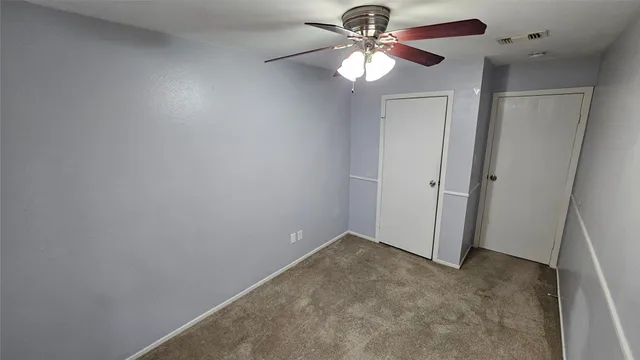 an empty room with a chandelier fan and a ceiling fan