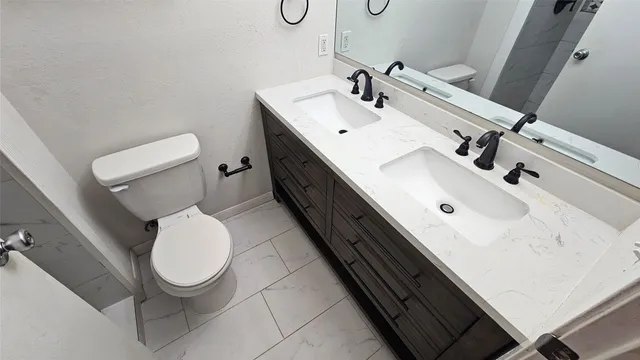 a bathroom with a double vanity sink toilet and mirror