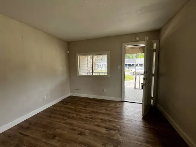 an empty room with wooden floor and windows