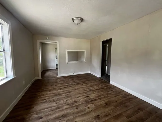 an empty room with wooden floor and windows
