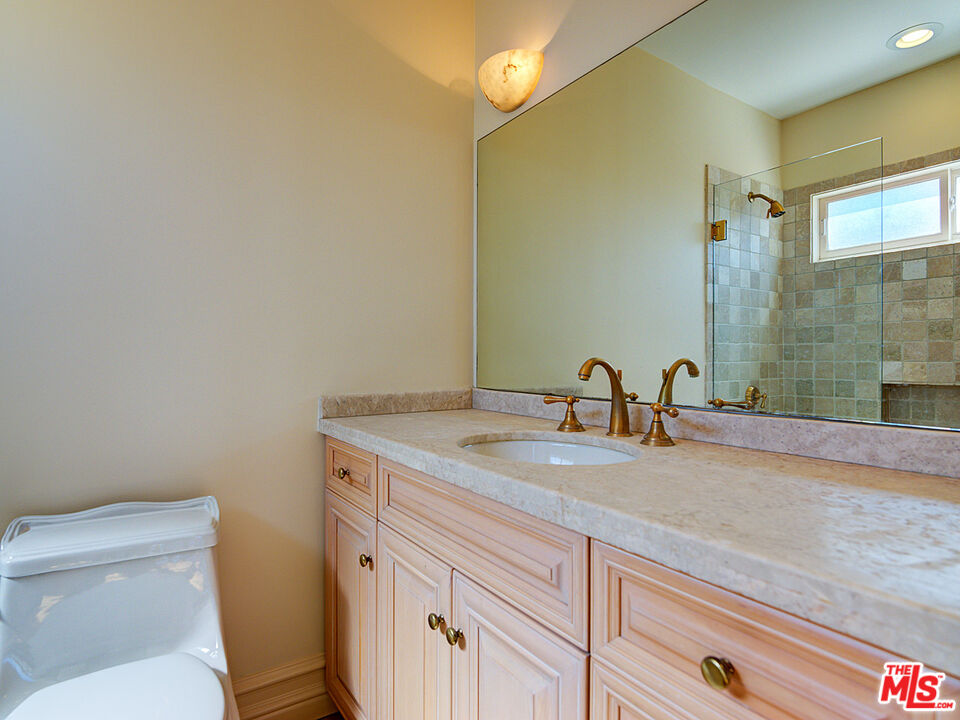 5003 Roma Court Venice, CA 90292 - Photo 24 of 34 a bathroom with a granite countertop sink a toilet and a mirror