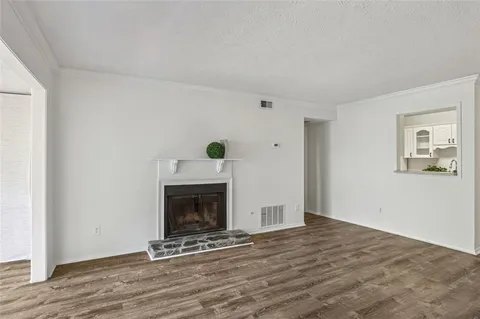 a view of an empty room with wooden floor and a fireplace