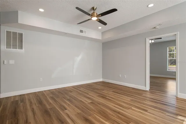 an empty room with wooden floor and a ceiling fan