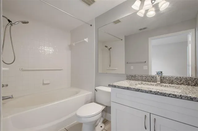 a bathroom with a granite countertop sink a toilet and bathtub