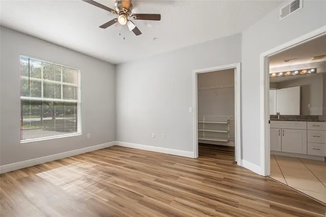 a view of an empty room with a window and wooden floor