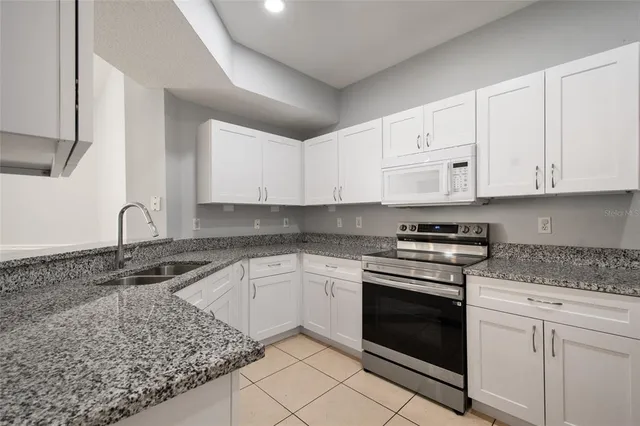 a kitchen with granite countertop white cabinets and appliances