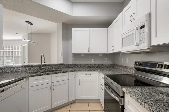 a kitchen with granite countertop a sink a stove and cabinets