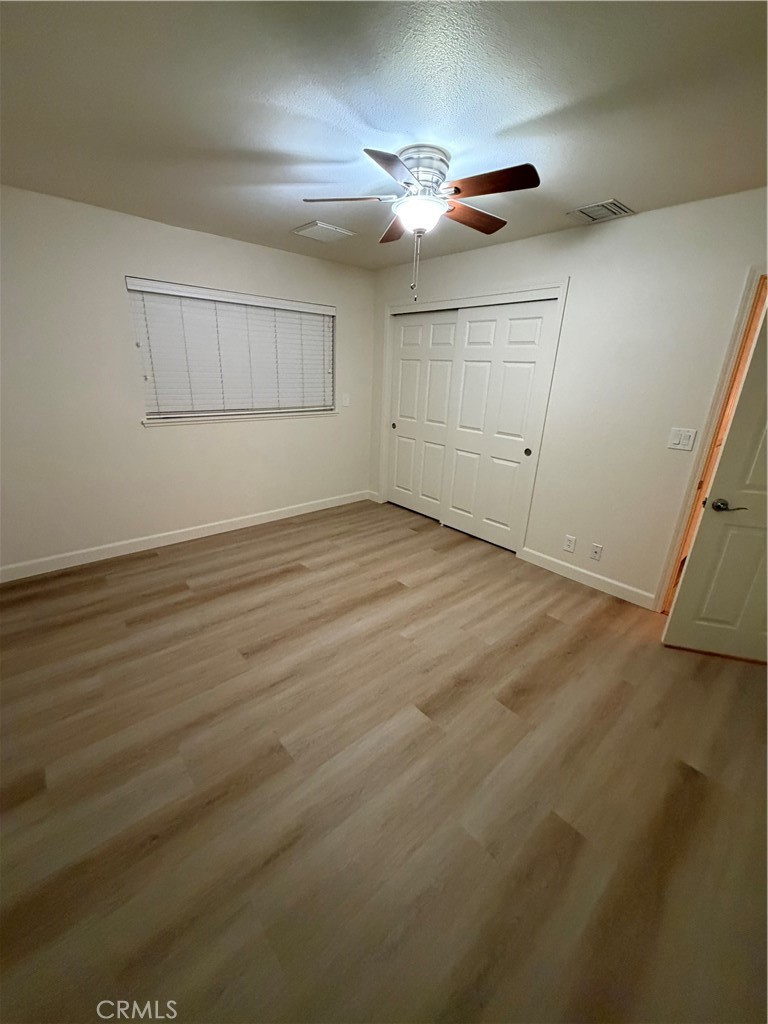 209 Kimberly Lane Ridgecrest, CA 93555 - Photo 56 of 62 an empty room with wooden floor fan and windows