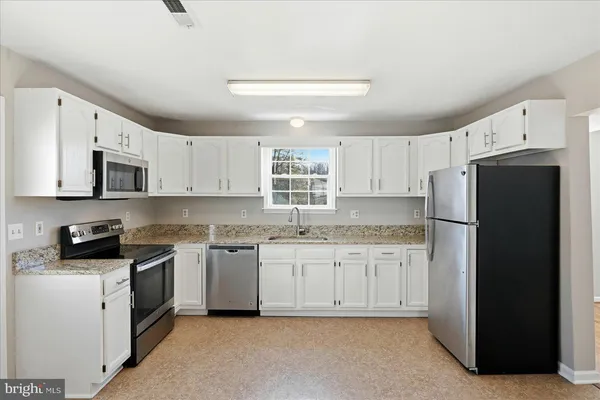 a kitchen with granite countertop white cabinets and window