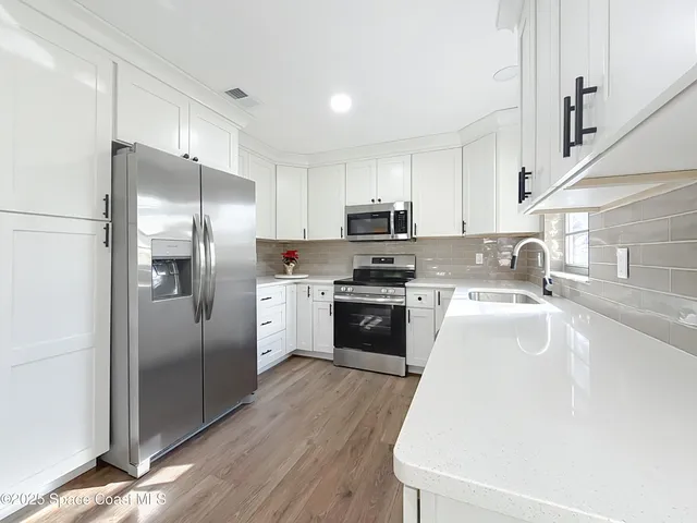 a kitchen with stainless steel appliances a refrigerator and a wooden floor