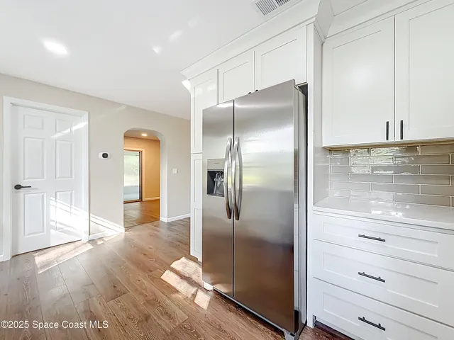 an empty room with wooden floor and a ceiling fan