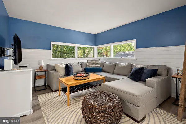 a living room with furniture a flat screen tv and a large window