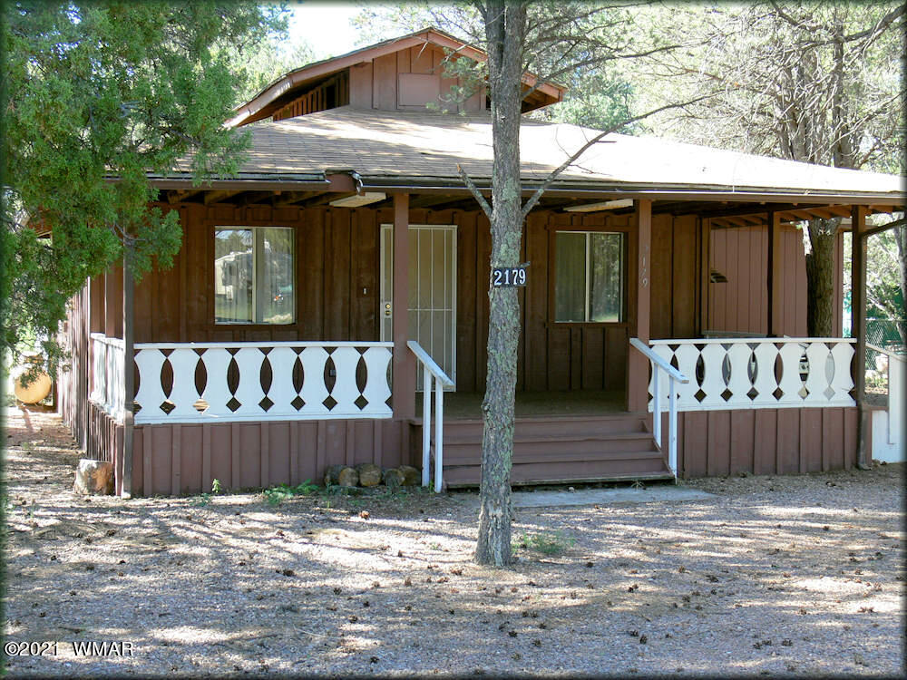 2179 Chevelon Road Overgaard, AZ 85933 - Photo 1 of 11 a view of a house with a wooden fence and a large tree