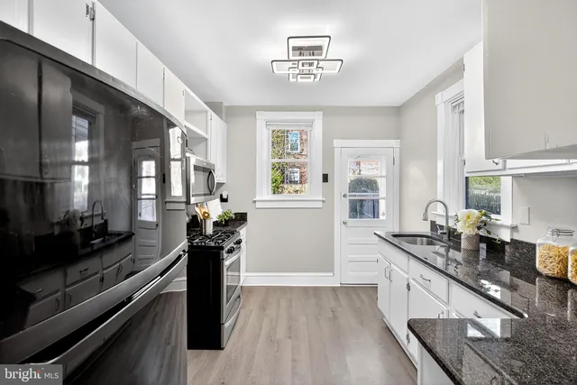 a kitchen with a counter top space a sink wooden floor and stainless steel appliances