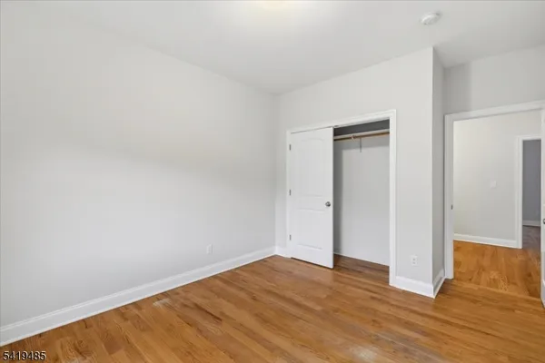 a view of an empty room with wooden floor and closet