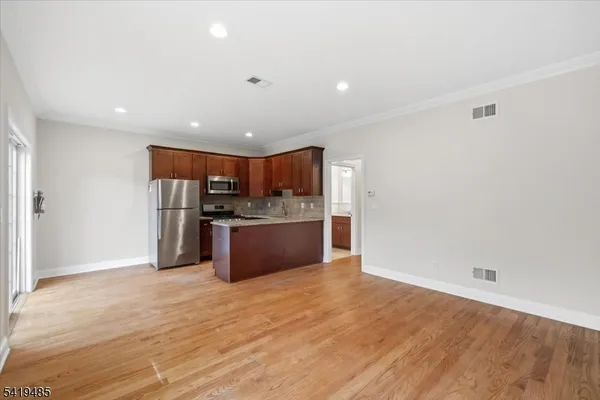 a kitchen with stainless steel appliances kitchen island a refrigerator sink and cabinets