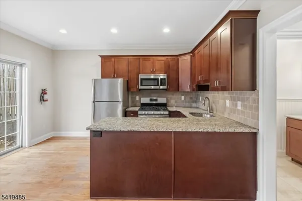 a kitchen with stainless steel appliances granite countertop a refrigerator a stove a sink and a microwave