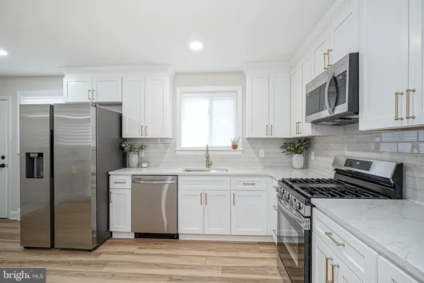 an empty room with wooden floor chandelier fan and windows