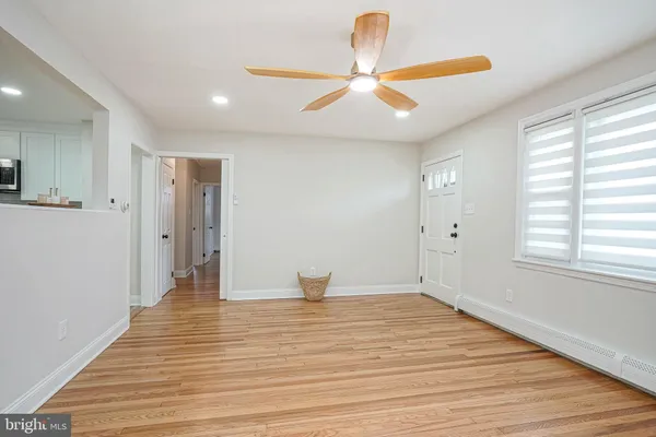 a view of an empty room with wooden floor and a ceiling fan