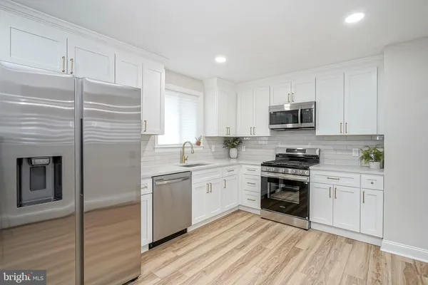 a kitchen with granite countertop a stove top oven a sink dishwasher and a refrigerator with wooden floor