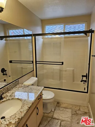a bathroom with a granite countertop sink toilet and shower