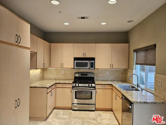 a kitchen with granite countertop a stove sink and cabinets