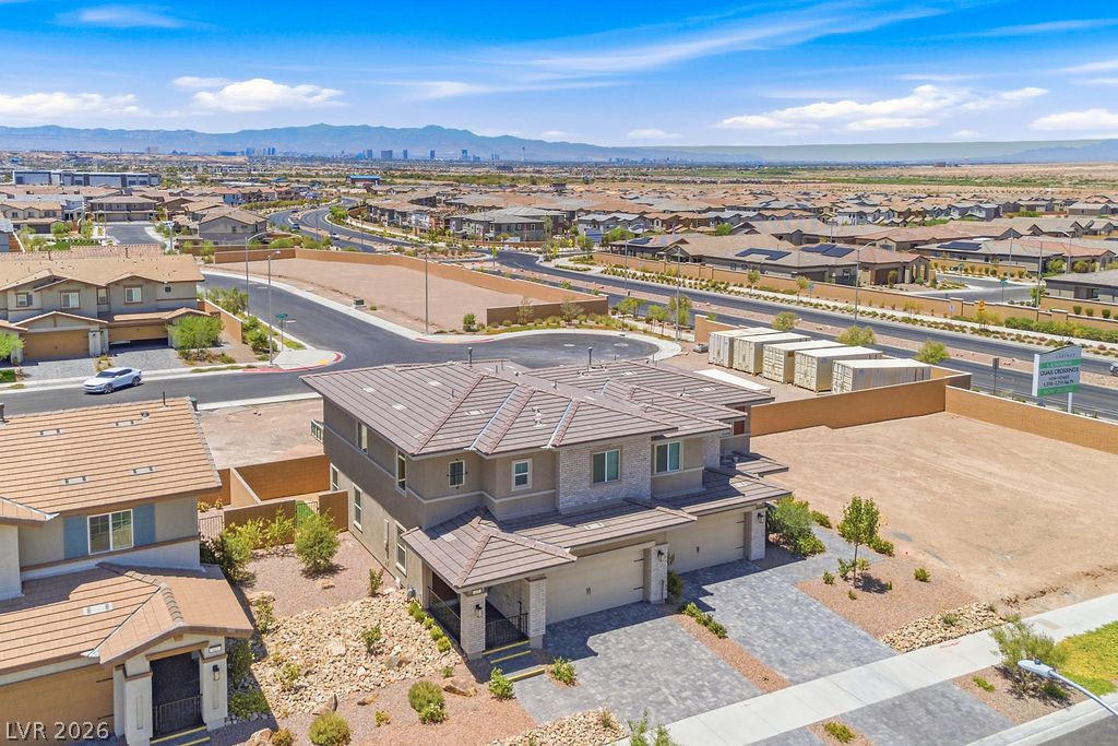 913 Cadence View Way Henderson, NV 89011 - Photo 2 of 46 An aerial perspective reveals a modern home with a two-car garage and a tile roof, nestled in a developing neighborhood.