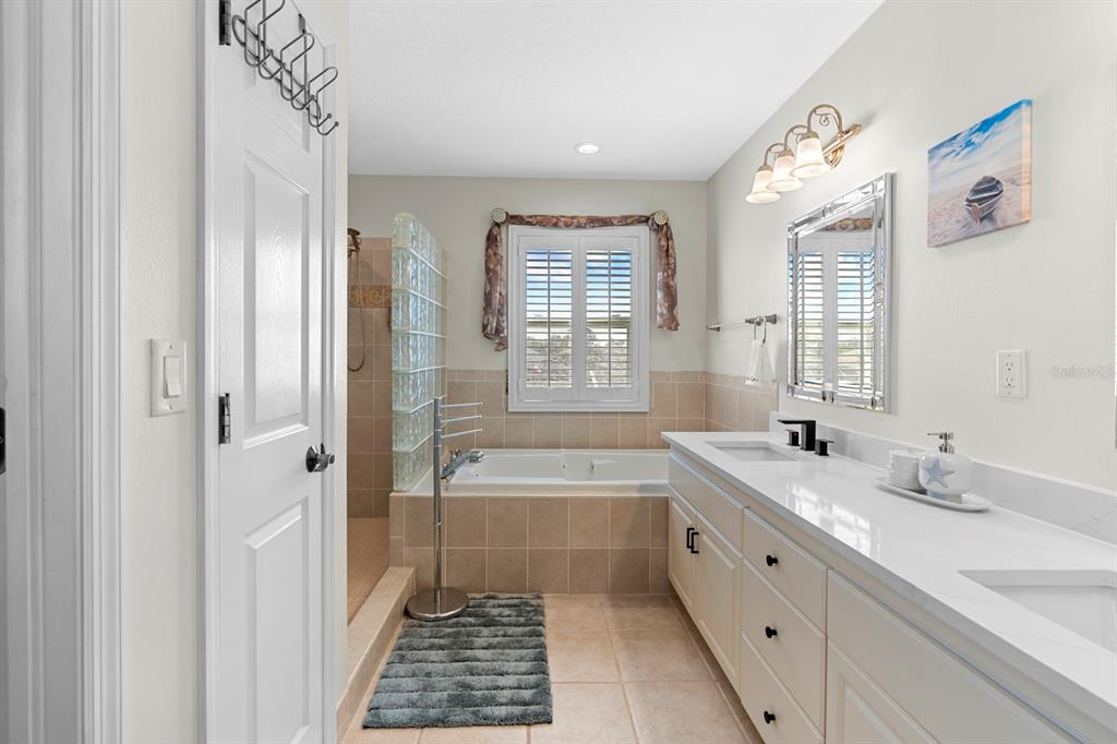 830 Golf Island Drive Apollo Beach, FL 33572 - Photo 65 of 87 a bathroom with a granite countertop sink a large mirror a bathtub and next to a window