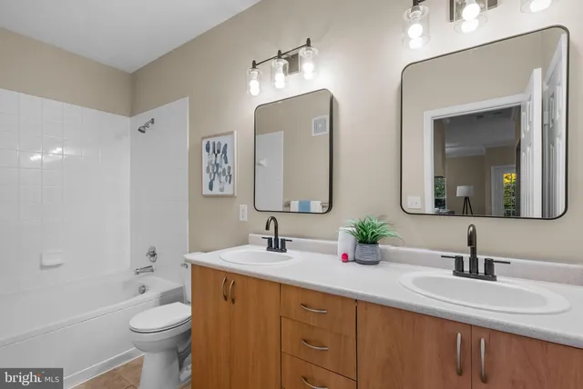 a bathroom with double vanity sinks a toilet a mirror and shower