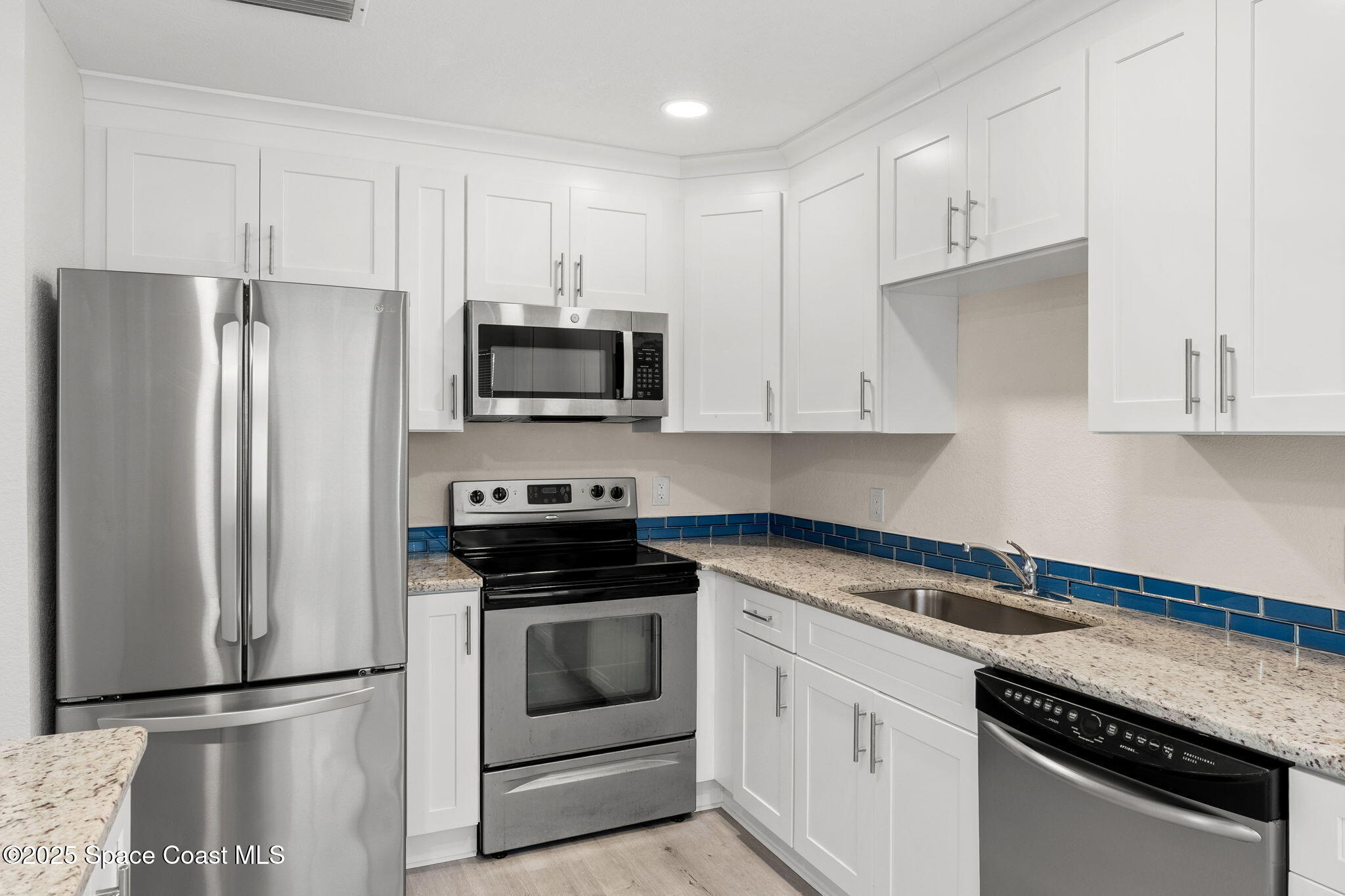 129 Seawind Drive, Unit 25 Satellite Beach, FL 32937 - Photo 8 of 28 a kitchen with granite countertop white cabinets and stainless steel appliances