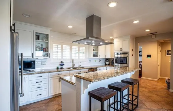 a kitchen with stainless steel appliances kitchen island granite countertop a sink stove cabinets and refrigerator